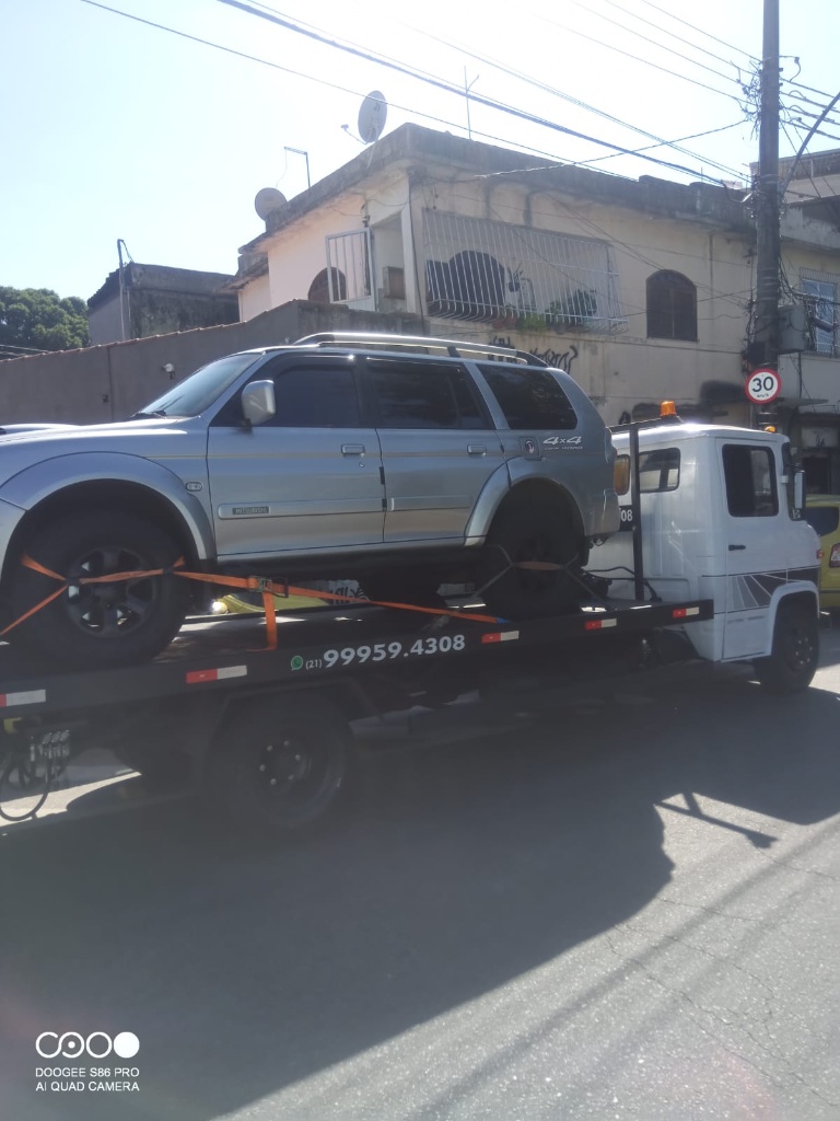 Utilitário 4x4 sendo transportado pela plataforma de guincho em área urbana.